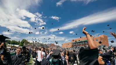 Graduates of the class of 2021 toss their mortarboards into the air on Memorial Field.