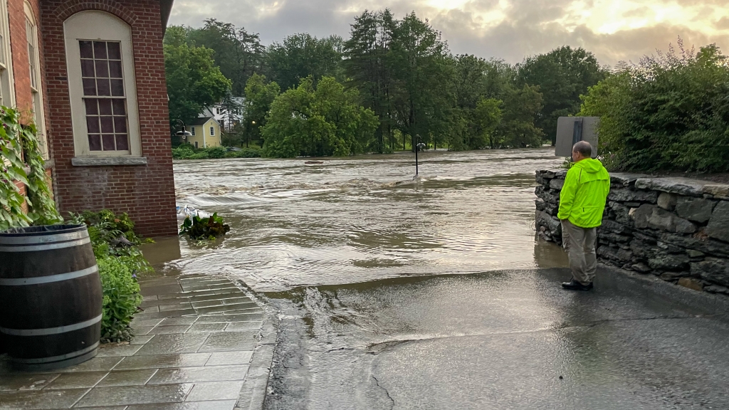 Workers watches flooding of Ottauquechee River